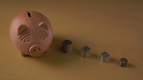 Clay-piggy-bank-and-stacks-of-colombian-pesos-coins