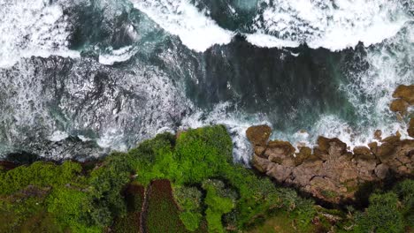 Aerial-overhead-shot-of-powerful-waves-of-sea-crashing-against-rocky-coastline
