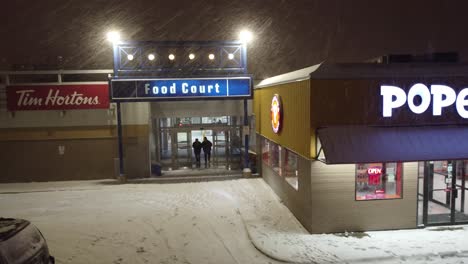 Toronto-Food-Court-in-Winter:-Heavy-Snowfall-and-Nighttime-at-Popeyes,-Tim-Hortons,-and-McDonald's