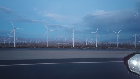 Driving-past-a-wind-turbines-on-the-side-of-the-highway-during-blue-hour