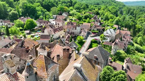 Small,-medieval-village-situated-next-to-a-river,-flowing-through-a-rich-forest-in-the-heart-of-France