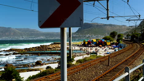 Dolly-in-along-railroad-track-of-colorful-iconic-St-James-beach-huts,-False-Bay