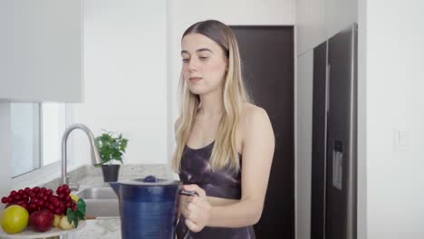 Young-athletic-girl-makes-healthy-juice-smoothie-for-diet-in-kitchen