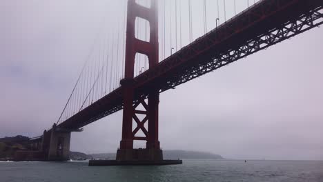 Gimbal-close-up-shot-from-a-moving-boat-as-it-passes-underneath-the-Golden-Gate-Bridge-on-a-foggy-day-in-San-Francisco,-California