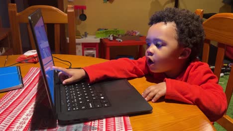 Playful-two-year-old-black-baby,-mix-raced,-clicks-the-keys-of-a-laptop-at-home