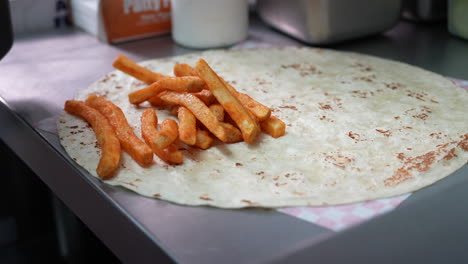 Adding-fries-while-making-a-California-Burrito---food-truck-series