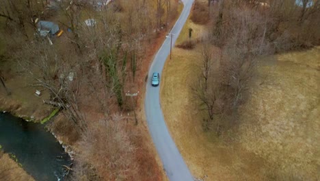 Aerial-View-of-vehicle-traveling-down-pathway-with-trees
