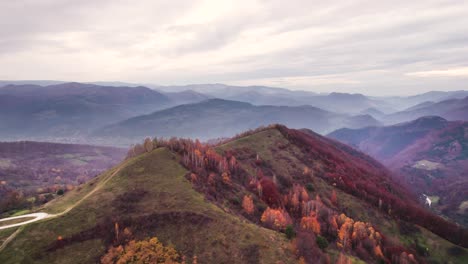 Aerial-panorama-of-green-hill-ridge-with-mountain-range-in-background,-Dumesti,-Transylvania