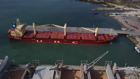 aerial-view-of-a-vessel-transporting-raw-material,-anchored-to-a-commercial-dock