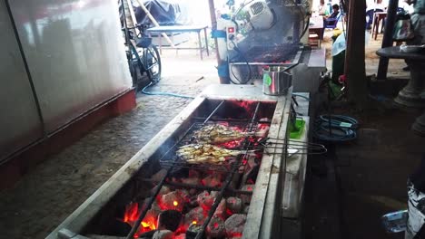 Grilling-Fish,-Traditional-Indonesian-Food-Market,-Beach-in-Sanur,-Bali,-Fire-of-the-Coals-on-the-Hot-Meat-between-Tongs,-Pasar-Sindhu