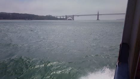 Gimbal-Aufnahme-Einer-Möwe,-Die-Auf-Den-Windströmungen-Entlang-Der-Seite-Eines-Bootes-Reitet,-Während-Es-Sich-Im-Nebel-Der-Golden-Gate-Bridge-In-San-Francisco-Nähert