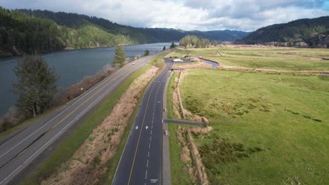 Beautiful-4K-aerial-shot-showcasing-passing-over-highway-next-to-Dean-Creek-in-Reedsport,-Oregon
