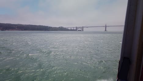 Gimbal-Aufnahme-Von-Der-Seite-Eines-Fahrenden-Bootes,-Das-Sich-Der-In-Nebel-Gehüllten-Golden-Gate-Bridge-Nähert