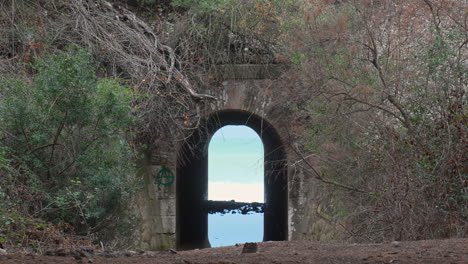 cyclist-rides-past-tunnel-leading-to-wild-sea