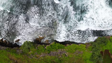 Overhead-drone-shot-of-sea-waves-hitting-the-rocks-on-the-cliff