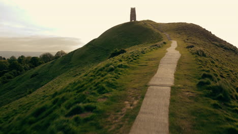 A-drone-shot-flying-along-a-foot-path-up-Glastonbury-Tor,-a-hill-in-Somerset-UK
