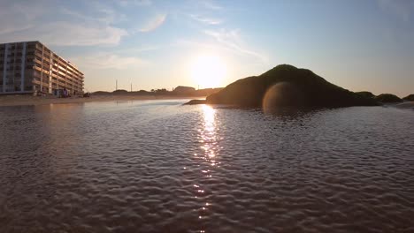 Waves-crashing-into-rock-on-beach-during-sunset