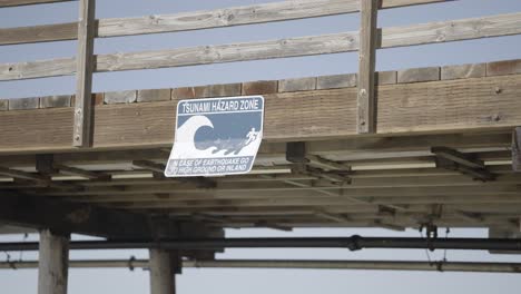 Tsunami-Hazard-Zone-Sign-on-California-Pier-with-a-Wave-on-Sign