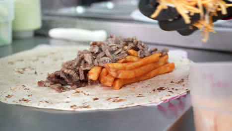 Hinzufügen-Von-Käse-Zu-Steak-Und-Pommes-Auf-Einem-Kalifornischen-Burrito-–-Food-Truck-Serie