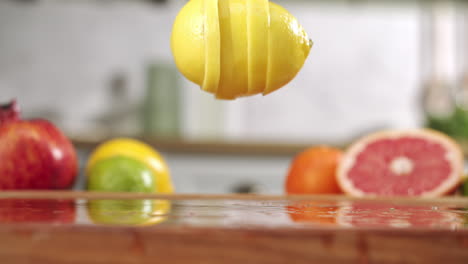 Slow-motion-of-sliced-lemon-falling-on-wet-wooden-board-in-a-kitchen