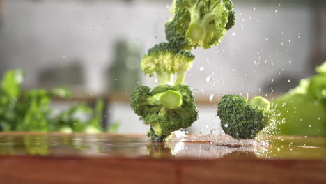 Slow-motion-of-fresh-green-broccoli-slices-falling-on-wet-wooden-board-in-a-kitchen