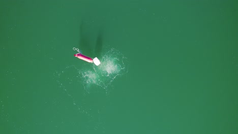 Aerial-view-of-a-red-buoy-in-a-lake,-air-divers-rise-to-the-surface