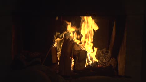 Orange-flames-burning-brightly-in-cozy-looking-fireplace,-filmed-as-medium-close-up-in-slow-motion