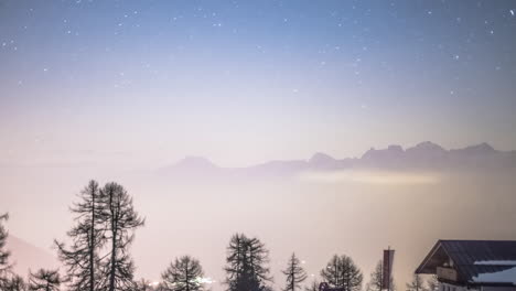 Stars-moving-over-the-silhouettes-of-the-alps-at-night-on-a-partly-cloudy-night