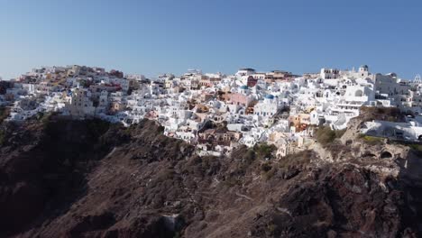 Flight-over-of-traditional-terraced-white-villas-ini-village-Oia,-Santorini,-Greece