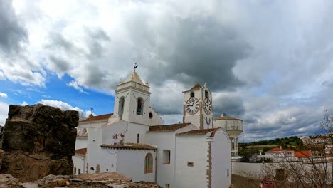 Zeitlose-Kirche-Santa-Maria-Tavira-Portugal-Ein-Wechselhafter-Frühlingstag-Mit-Vorbeiziehenden-Stürmischen-Wolken