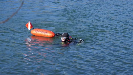A-diver-swims-out-to-sea-with-his-red-rescue-buoy