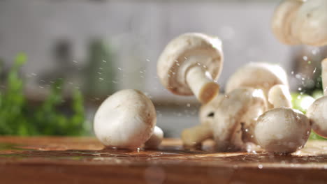 Slow-motion-of-fresh-mushrooms-falling-on-wet-wooden-board-in-a-kitchen