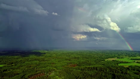 Große-Regenschauer-Ziehen-Mit-Einem-Großen-Regenbogen-über-Die-Grüne-Natur
