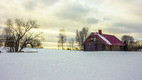Time-lapse-shot-of-golden-sunset-behind-house-during-snowy-day-in-rural-area---Clouds-flying-at-sky