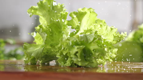 Zeitlupe-Von-Frischem-Grünen-Salat,-Der-In-Einer-Küche-Auf-Ein-Nasses-Holzbrett-Fällt