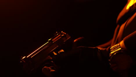 Male-hand-holding-gun-on-black-background,-colored-back-lights