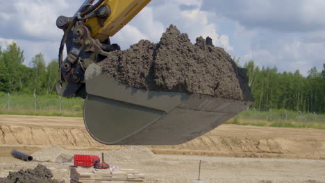Bucket-of-an-excavator-full-of-dirt---digging-at-a-new-construction-site-in-slow-motion