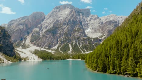 Aerial-Drone-shot-of-a-drone-above-the-river-with-the-Dolomites-Alps-in-the-back,-Lago-di-Braies,-Italy,-Dolomites