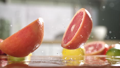 Slow-motion-of-sliced-in-half-grapefruit-falling-on-wet-wooden-board-in-a-kitchen