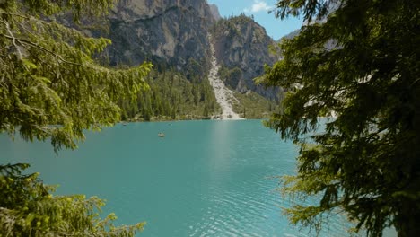 Aerial-Drone-shot-coming-through-the-forest-to-the-river,-Lago-di-Braies,-Italy,-Dolomites