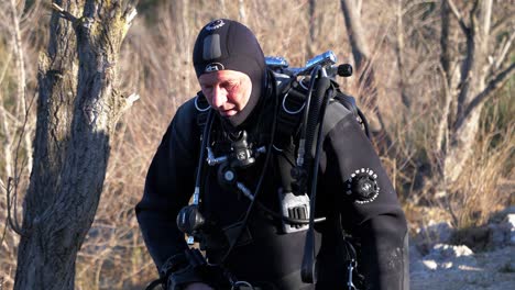 A-diver-dressed-in-black-with-his-oxygen-cylinders-descends-from-the-forest-to-the-lake