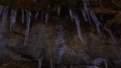 Icicles-on-the-side-of-a-sandstone-cliff-melt,-drip-and-refreeze-as-shadows-indicate-the-movement-of-the-sun---time-lapse