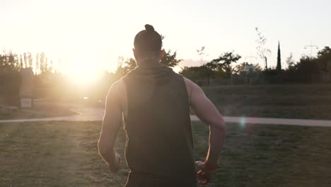 A-sportsman-runs-towards-the-setting-sun,-his-back-is-in-a-tank-top