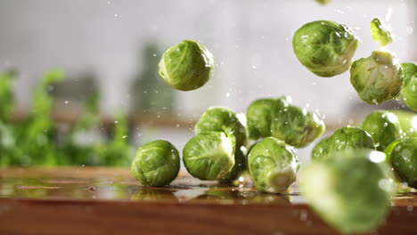 Slow-motion-of-fresh-brussels-sprouts-falling-on-wet-wooden-board-in-a-kitchen
