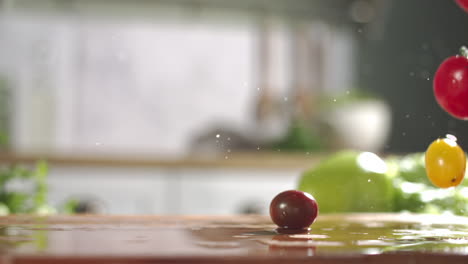 Slow-motion-of-variety-of-cherry-tomatos-falling-on-wet-wooden-board-in-a-kitchen