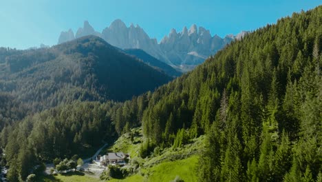 Aerial-drone-shot-of-the-Dolomites-in-the-church-of-San-Giovanni-in-Ranui-with-the-forest-and-the-alps-in-the-back,-Italy,-Dolomites