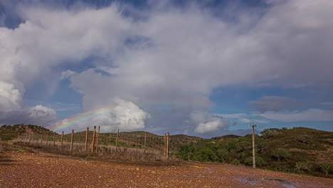 Cloudscape-and-a-rainbow-over-a-countryside-landscape-in-Europe---time-lapse