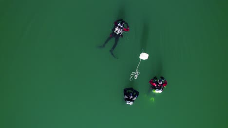 Divers-in-a-lake-swim-on-the-surface-with-their-buoys-and-scuba-tank