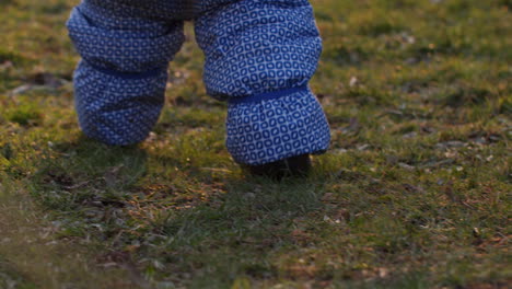 Close-up-shot-of-a-child-wearing-an-snowsuit-walking-on-grass-in-beautiful-evening-light