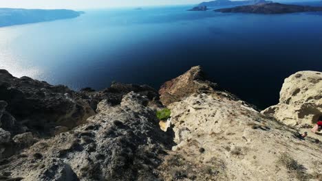 Drone-diving-Santorini-cliff-coastline,-travel-concept